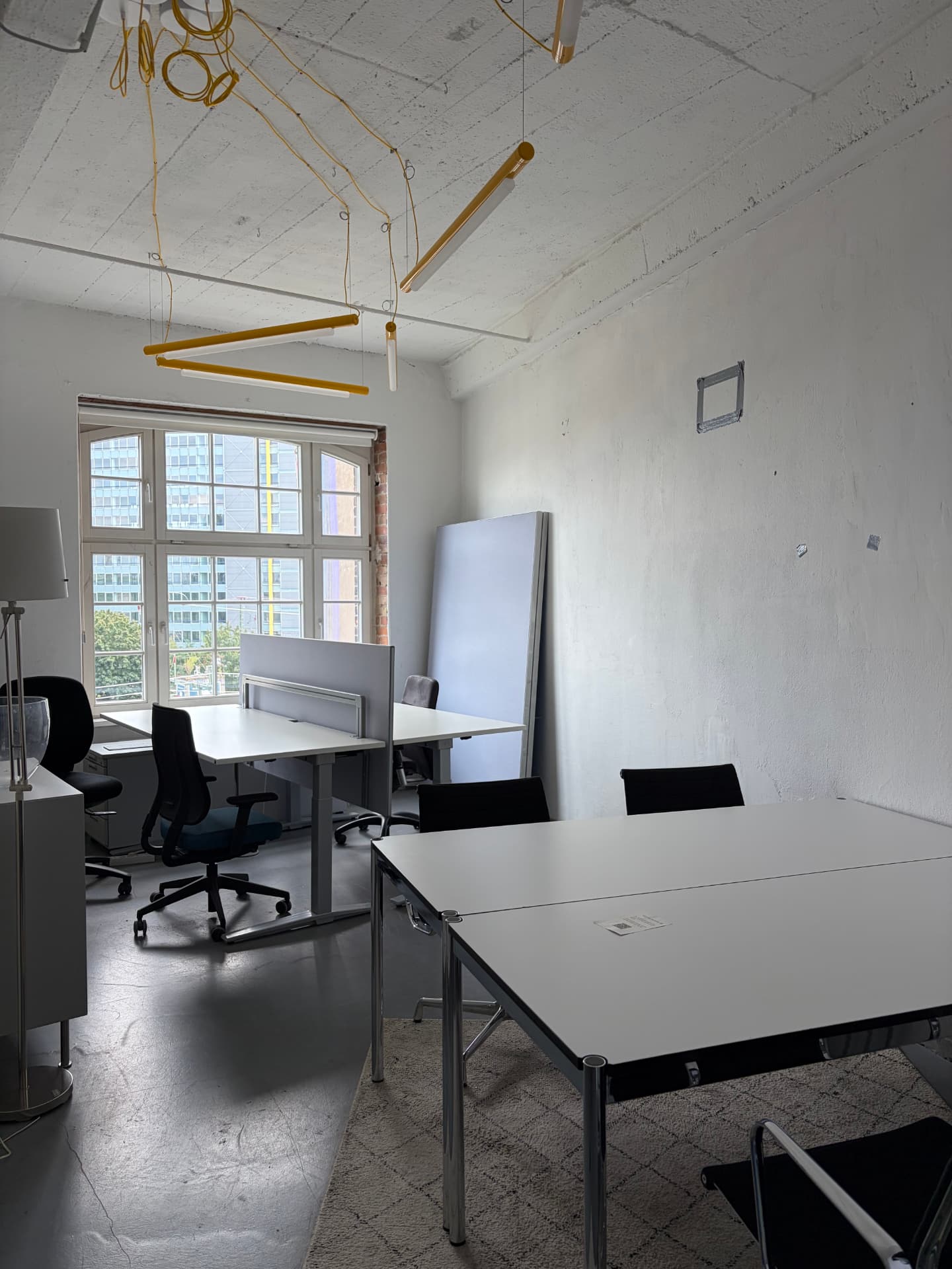 Teamraum mit zwei Arbeitsplätzen, großen Fenstern und gelben Pendelleuchten