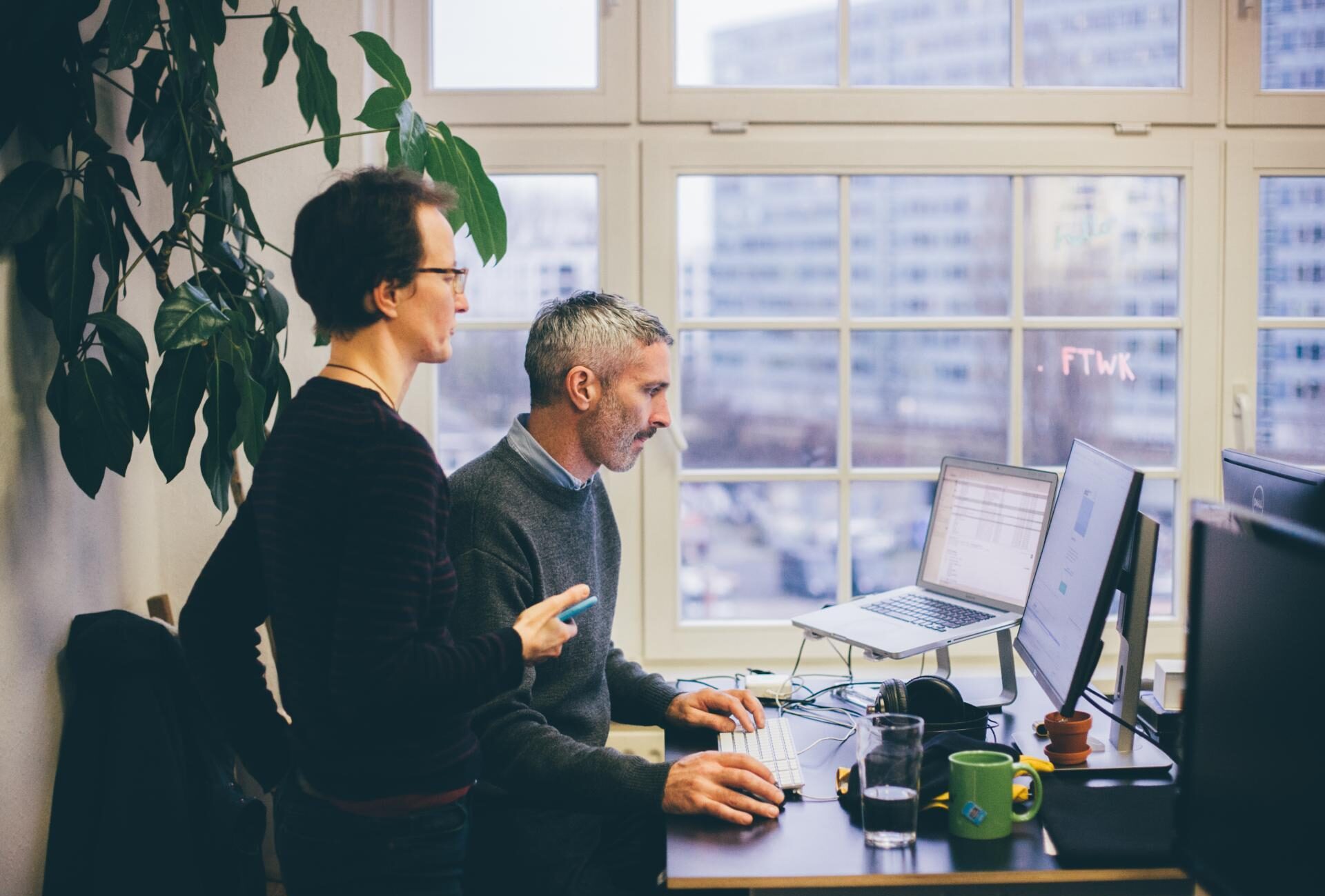 Zwei Techies arbeiten gemeinsam an einem Schreibtisch im Coworking-Space